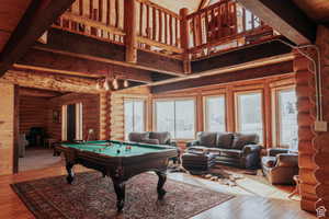 Rec room featuring rustic walls, hardwood / wood-style floors, billiards, and a high wood beamed ceiling