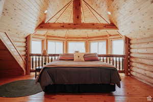 Bedroom with log walls, wood-type flooring, and a high wooden beamed ceiling