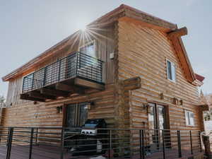 Back of house featuring a balcony, log exterior, and a deck