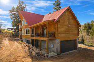 View of home's exterior with an attached garage, driveway, log exterior, and a metal roof