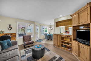 Living room with light wood-type flooring and hanging lights