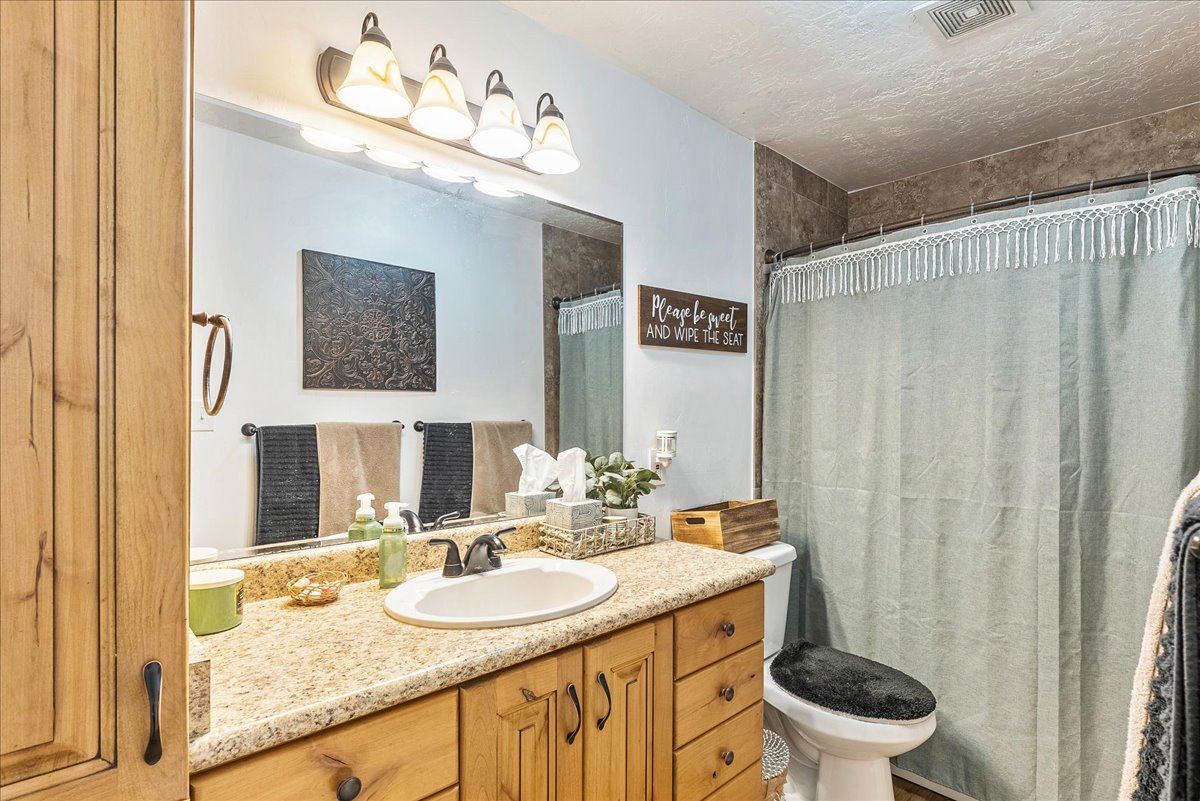 Bathroom with vanity, curtained shower, and a textured ceiling