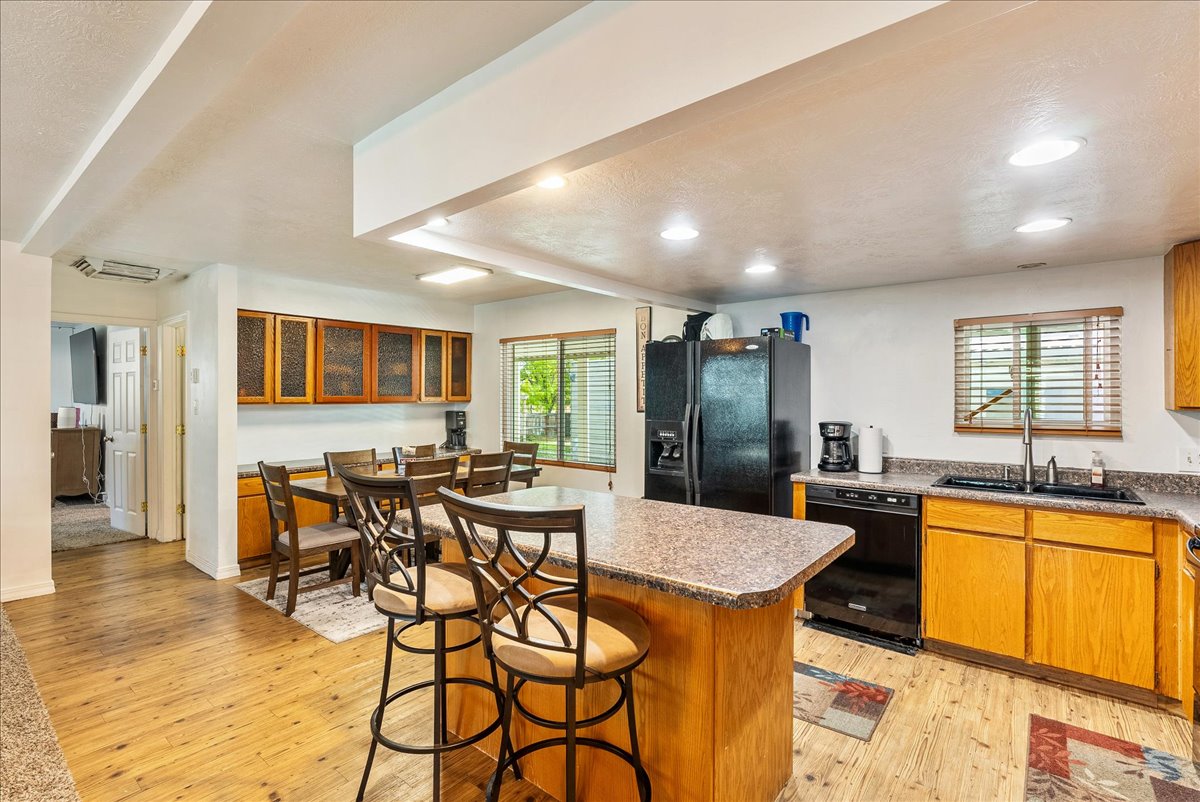 Kitchen featuring light wood-style flooring, black appliances, a breakfast bar area, a kitchen island, and wood finish cabinetry