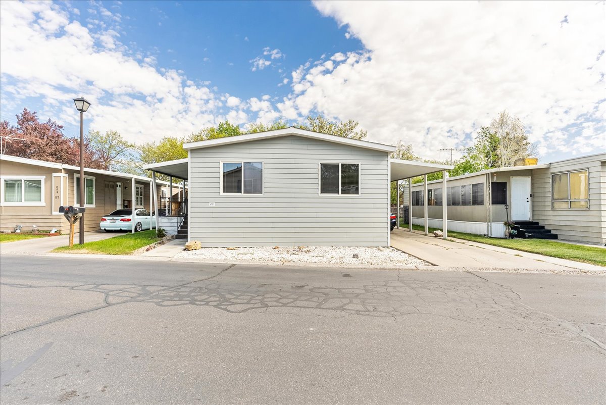 Manufactured / mobile home featuring a carport, entry steps, and driveway