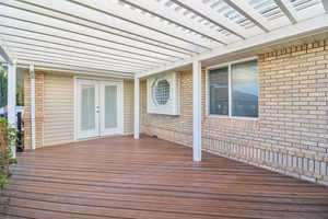 Wooden deck featuring french doors and a pergola