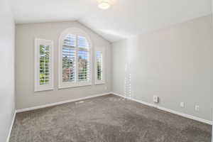 Unfurnished room with dark colored carpet and baseboards