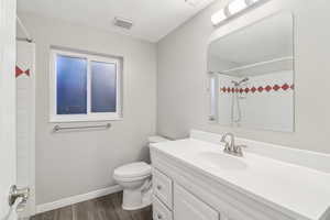Full bath with vanity, dark wood-type flooring, a shower, and a textured ceiling