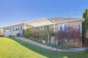 Back of property featuring brick siding, a yard, a deck, and a pergola