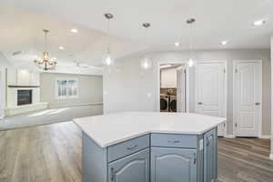 Kitchen featuring washing machine and dryer, light wood-style flooring, a fireplace, blue cabinetry, and lofted ceiling