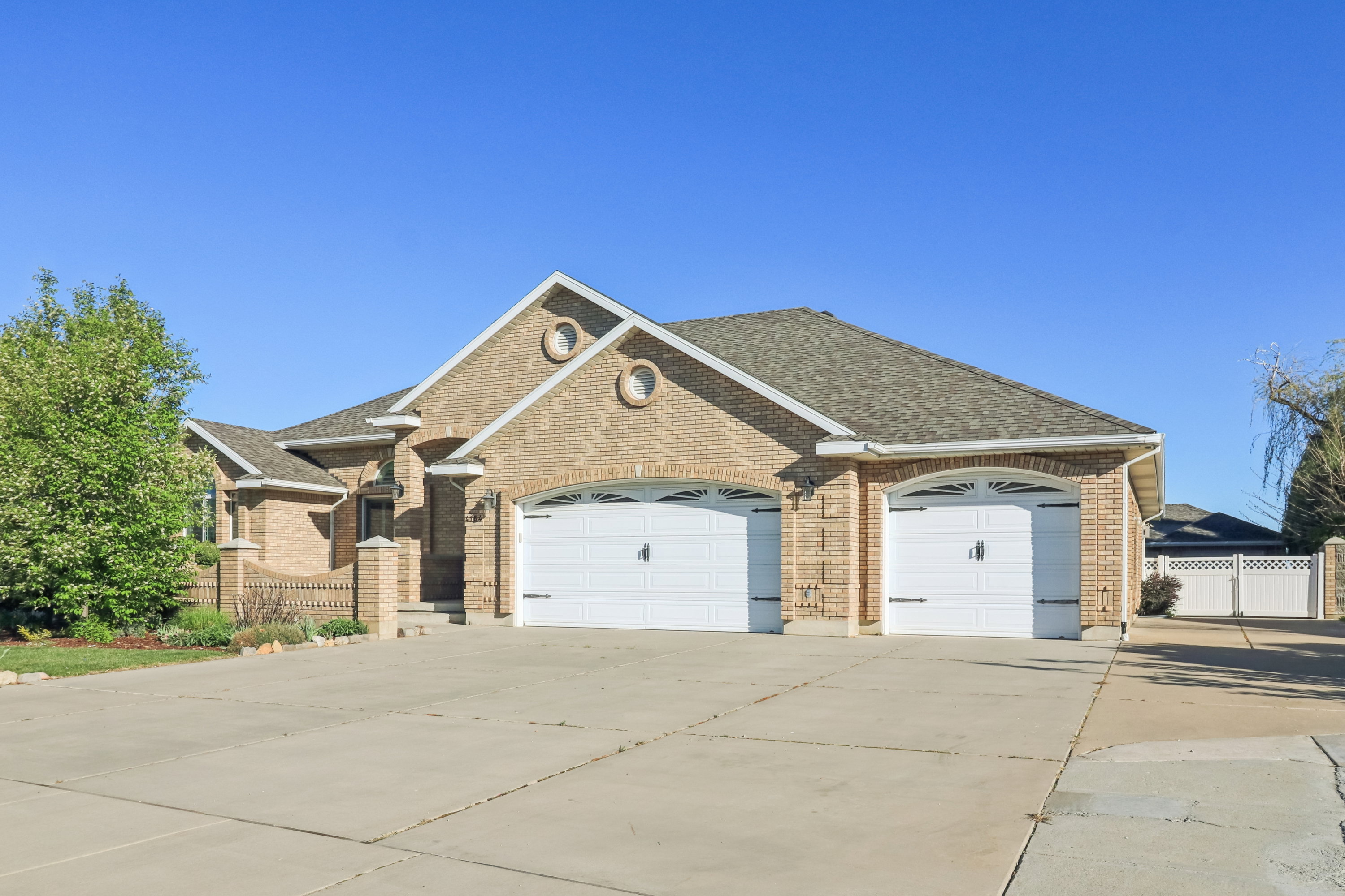 View of front facade with a garage, concrete driveway, roof with shingles, and brick siding