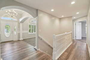 Entrance foyer featuring hardwood / wood-style flooring, arched walkways, and a chandelier