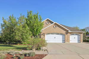 View of front of property with a garage, driveway, brick siding, and a shingled roof