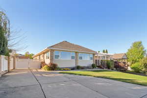 View of front of house with a front lawn, a gate, driveway, and roof with shingles