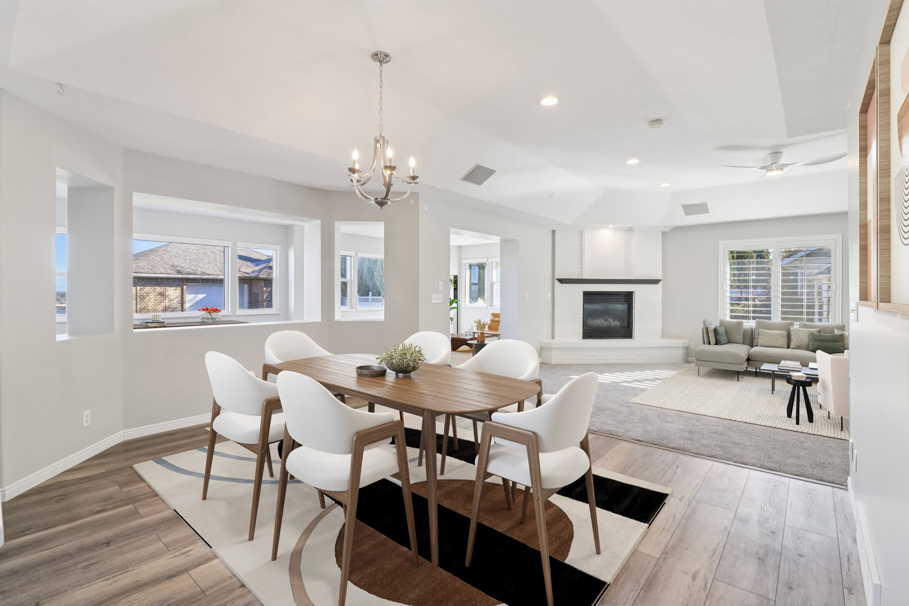 Dining area featuring light wood-type flooring, suspended lighting, a fireplace, and vaulted ceiling