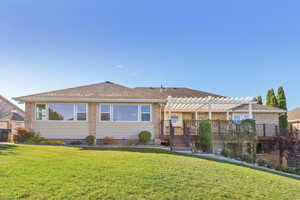 Back of house featuring a lawn, brick siding, a shingled roof, and a pergola