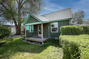 Back of property with concrete block siding, a yard, a wooden deck, and roof with shingles