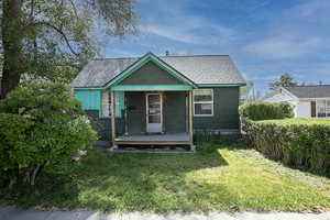 Bungalow-style house with a front yard, a shingled roof, and a porch