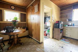 Kitchen featuring light flooring, an ornate ceiling, open shelves, wood walls, and stainless steel microwave