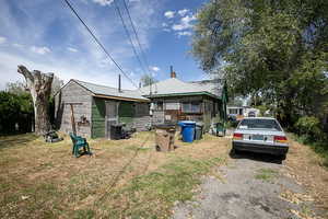 Back of property featuring a chimney, a yard, and a shingled roof