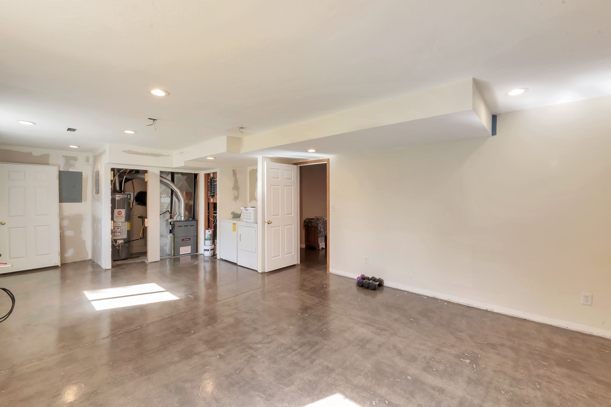 Finished basement featuring heating unit, gas water heater, recessed lighting, and electric panel