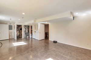 Finished basement featuring heating unit, gas water heater, recessed lighting, and electric panel