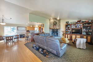 Living area with a stone fireplace, vaulted ceiling, and light wood-type flooring