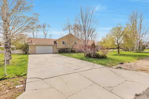 Tri-level home featuring a front yard, a garage, and driveway