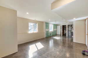 Spare room featuring finished concrete floors, recessed lighting, heating unit, and secured water heater