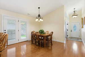 Dining space with lofted ceiling, light wood-style floors, and a chandelier