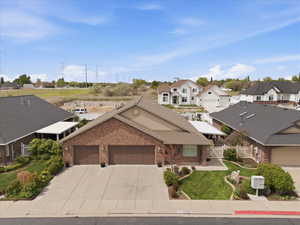 View of front of home featuring a garage, brick siding, driveway, and a residential view