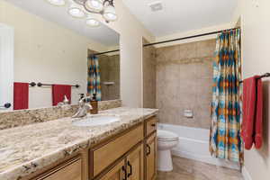 Full bathroom with vanity, shower / bath combination with curtain, and light tile patterned flooring