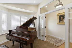 Sitting room with vaulted ceiling, carpet, and healthy amount of natural light