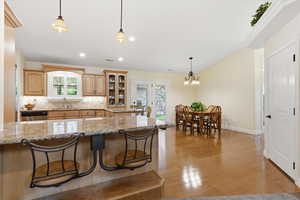 Kitchen with light wood finish cabinetry, tasteful backsplash, a kitchen bar, and plenty of natural light