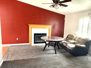 Carpeted living area featuring a ceiling fan and a tiled fireplace
