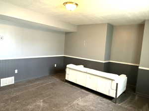 Interior space featuring a wainscoted wall, dark colored carpet, and wood walls