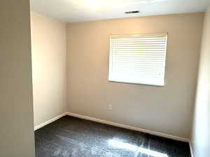 Unfurnished room featuring baseboards and dark colored carpet