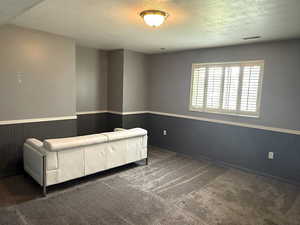 Sitting room featuring wainscoting, a textured ceiling, dark carpet, and wooden walls