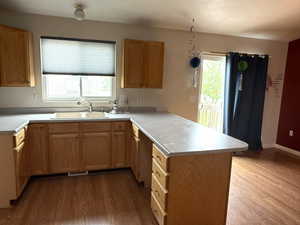 Kitchen featuring a peninsula, dark wood finished floors, light countertops, and wood finish cabinetry