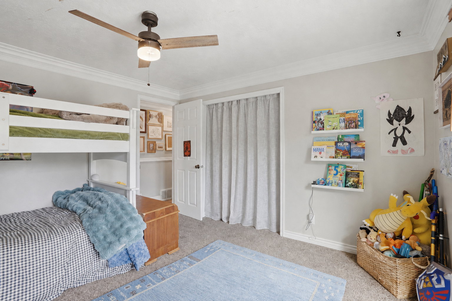 Neutral-toned room featuring a ceiling fan with wood-finish blades, crown molding, and carpeted flooring