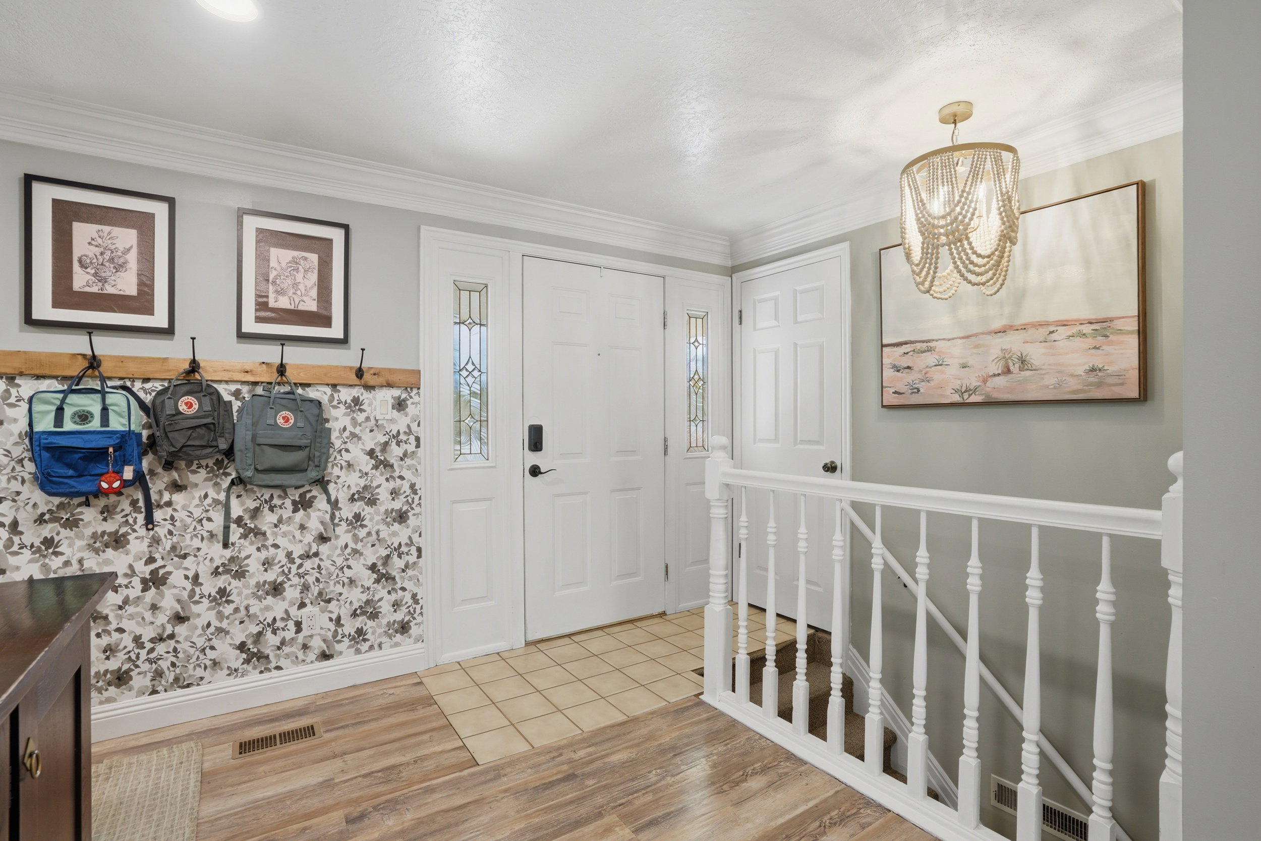 Entryway with light wood finished floors, ornamental molding, and a chandelier