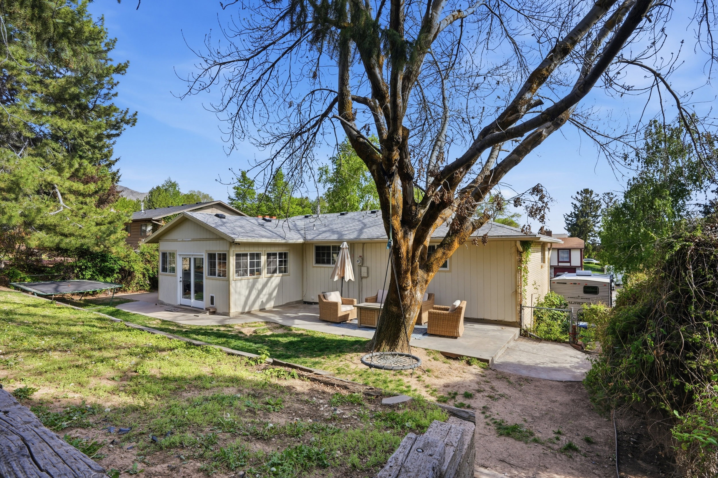 Back of property featuring a patio area, outdoor seating, roof with shingles, and a yard
