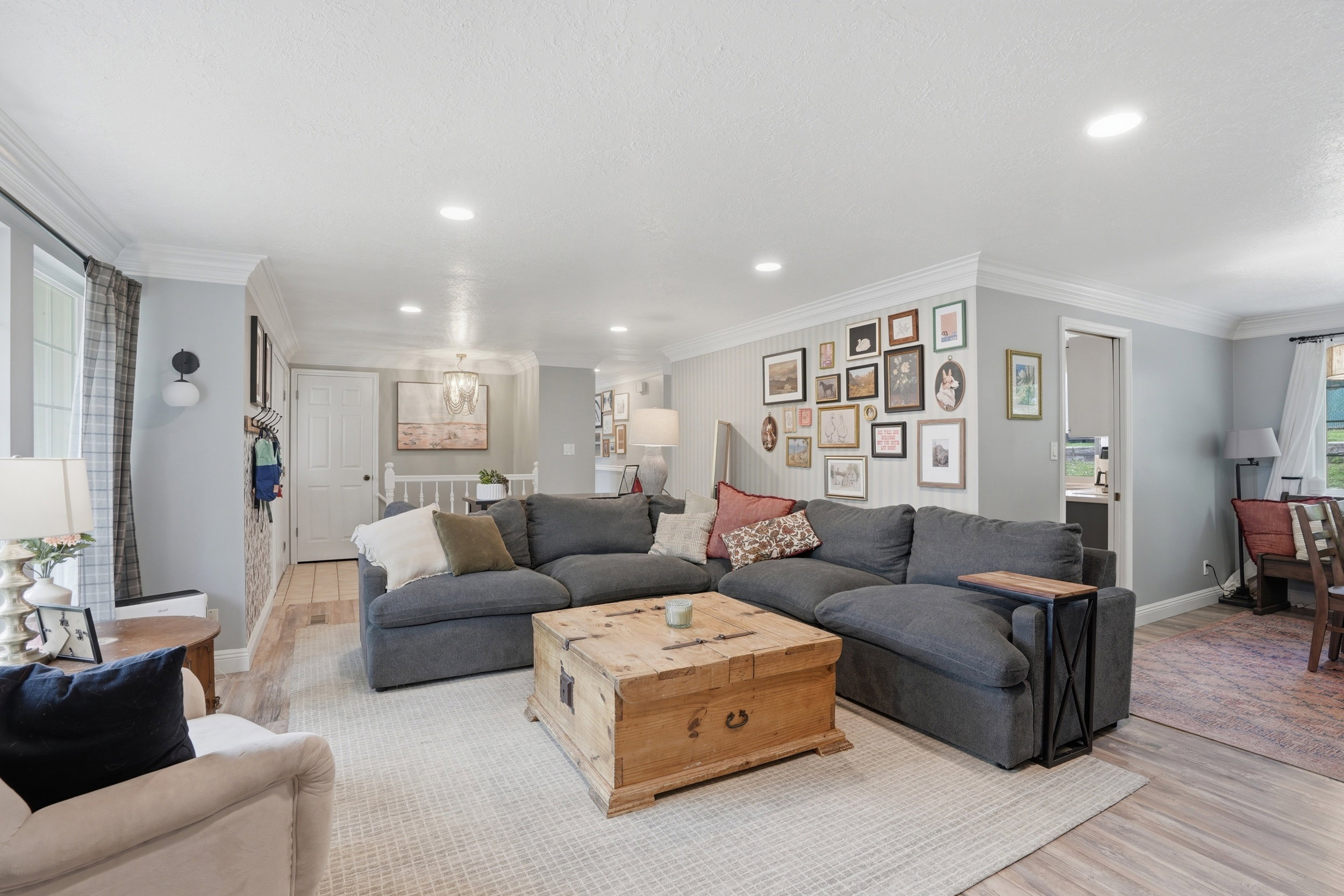 Living area featuring light wood-style floors, crown molding, and suspended lighting