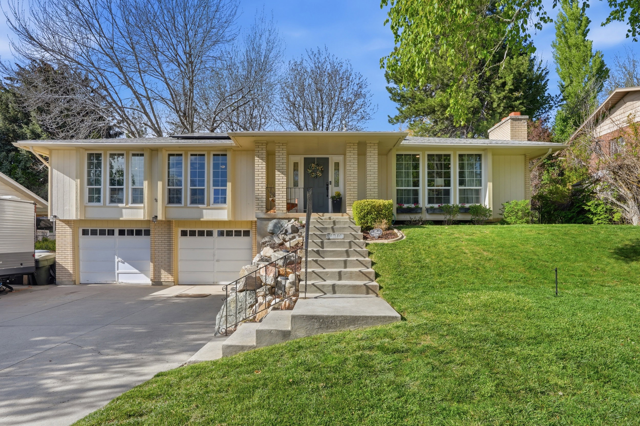 Ranch-style house with solar panels, brick siding, an attached garage, a front lawn, and concrete driveway