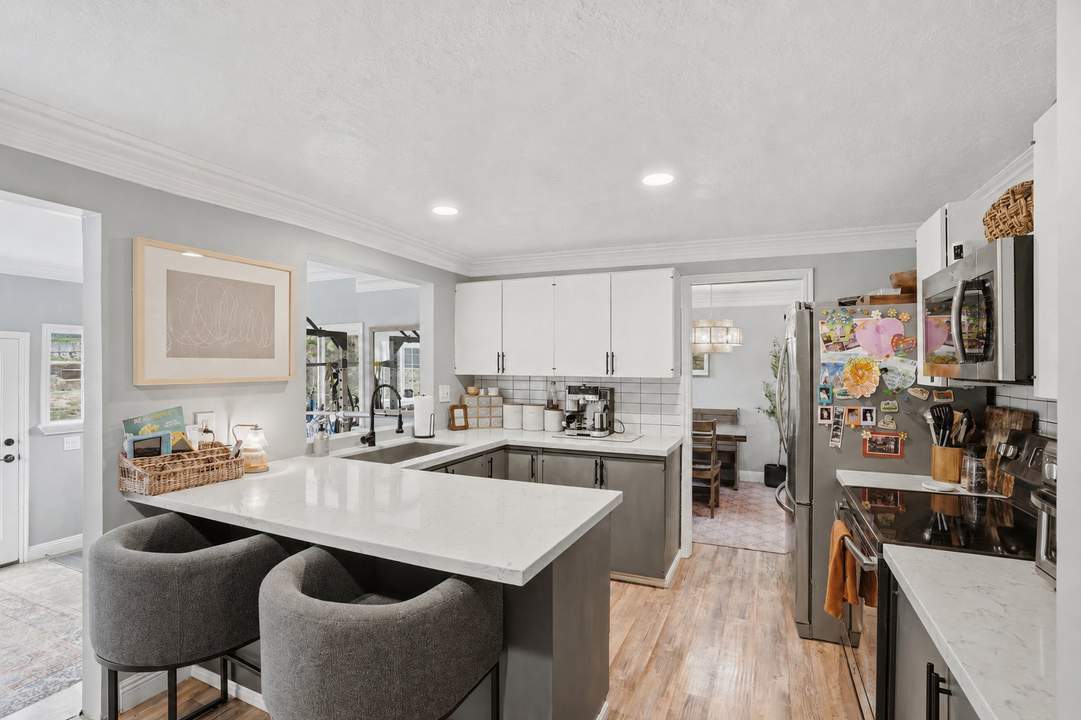 U-shaped kitchen featuring white upper cabinetry, grey lower cabinetry, stainless steel appliances, wood-finish flooring, and white countertops