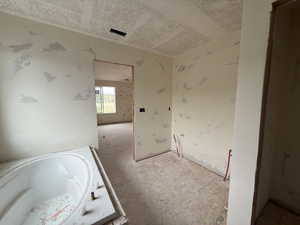 Full bath featuring a garden tub and a textured ceiling