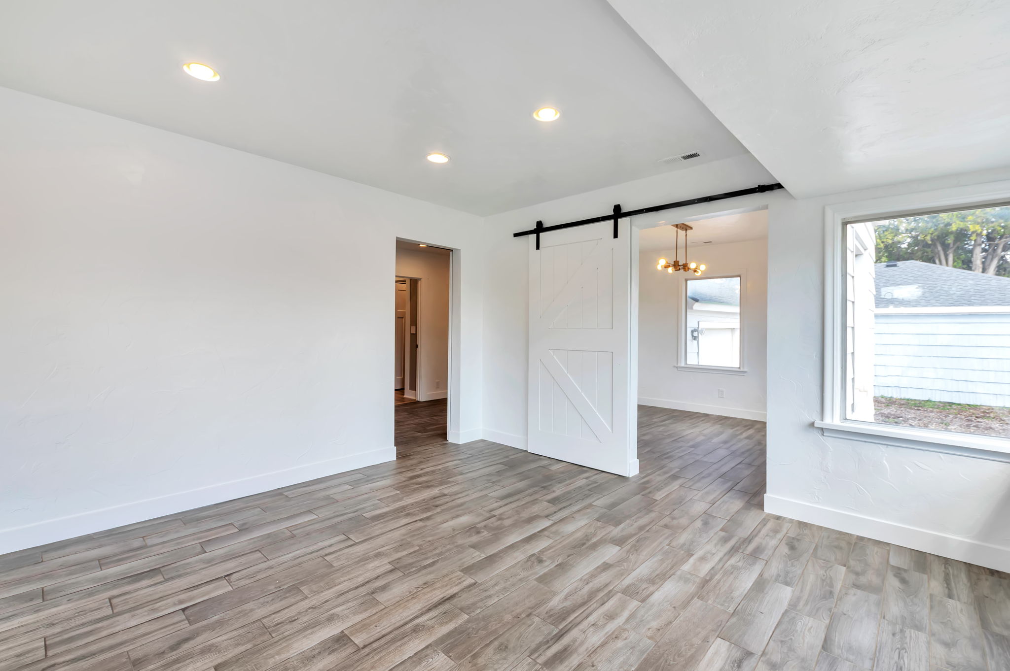 Unfurnished room featuring a barn door, light wood-type flooring, and recessed lighting