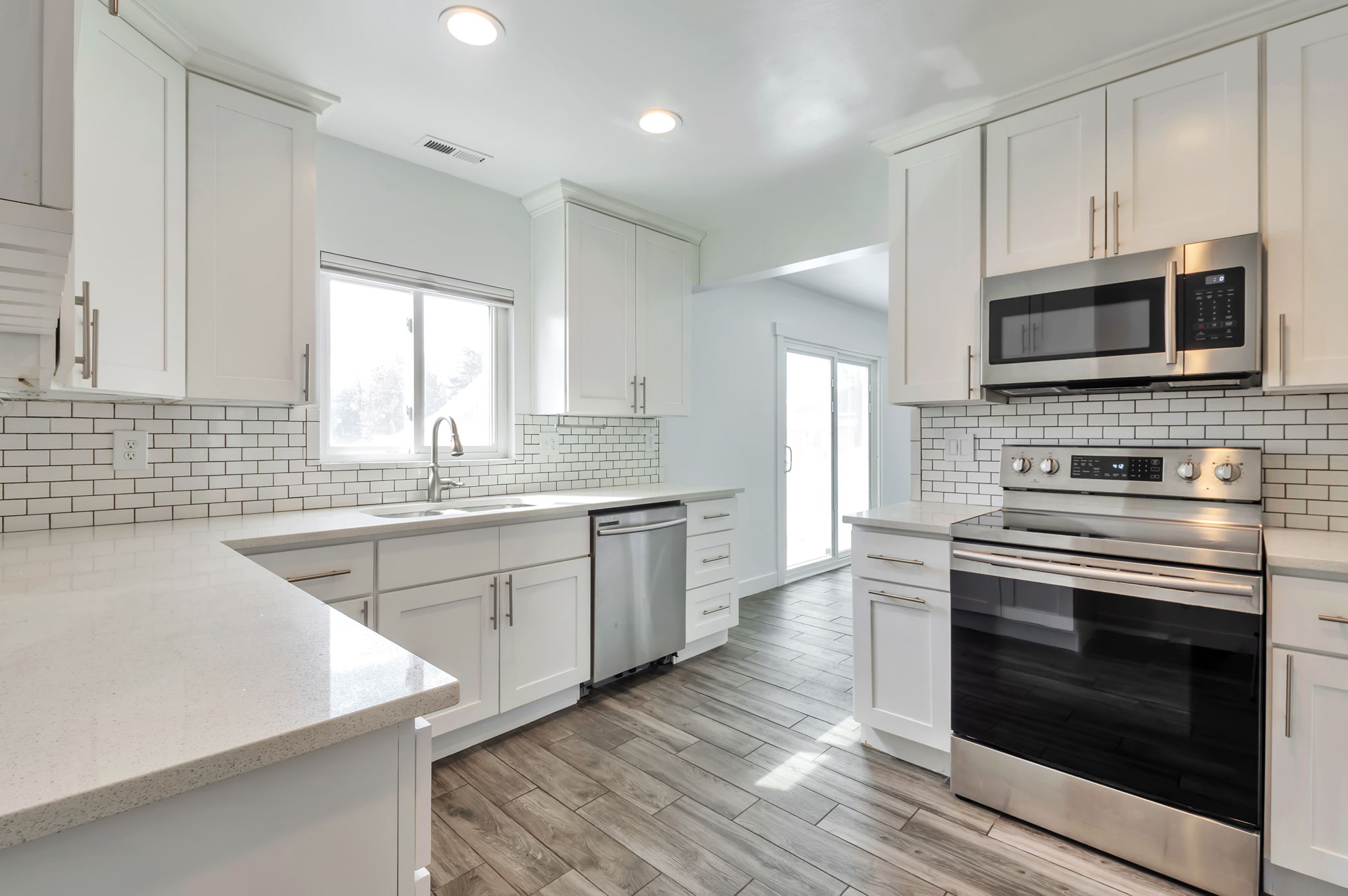 Kitchen with stainless steel appliances, white cabinetry, light wood-type flooring, and recessed lighting