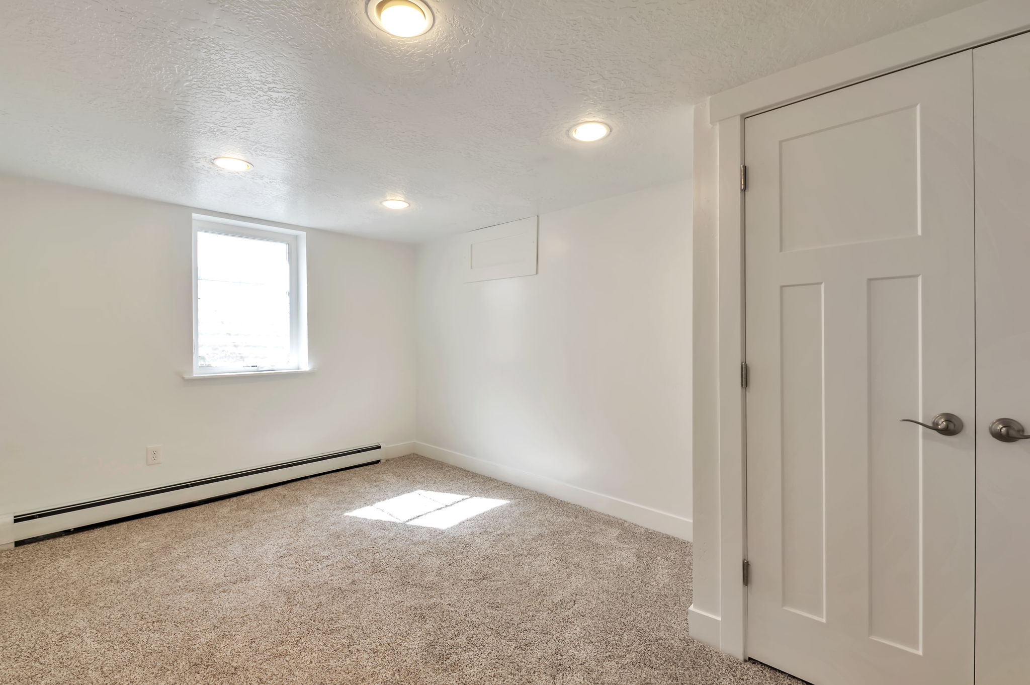 Basement with a textured ceiling, baseboard heating, light colored carpet, and recessed lighting