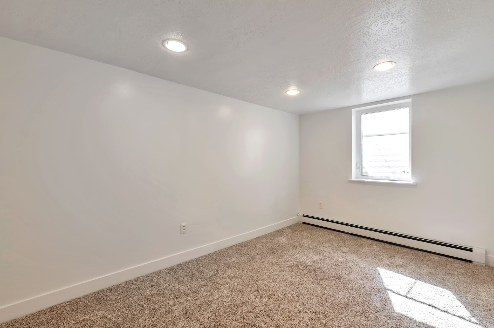 Unfurnished room featuring a baseboard radiator, light carpet, a textured ceiling, and recessed lighting
