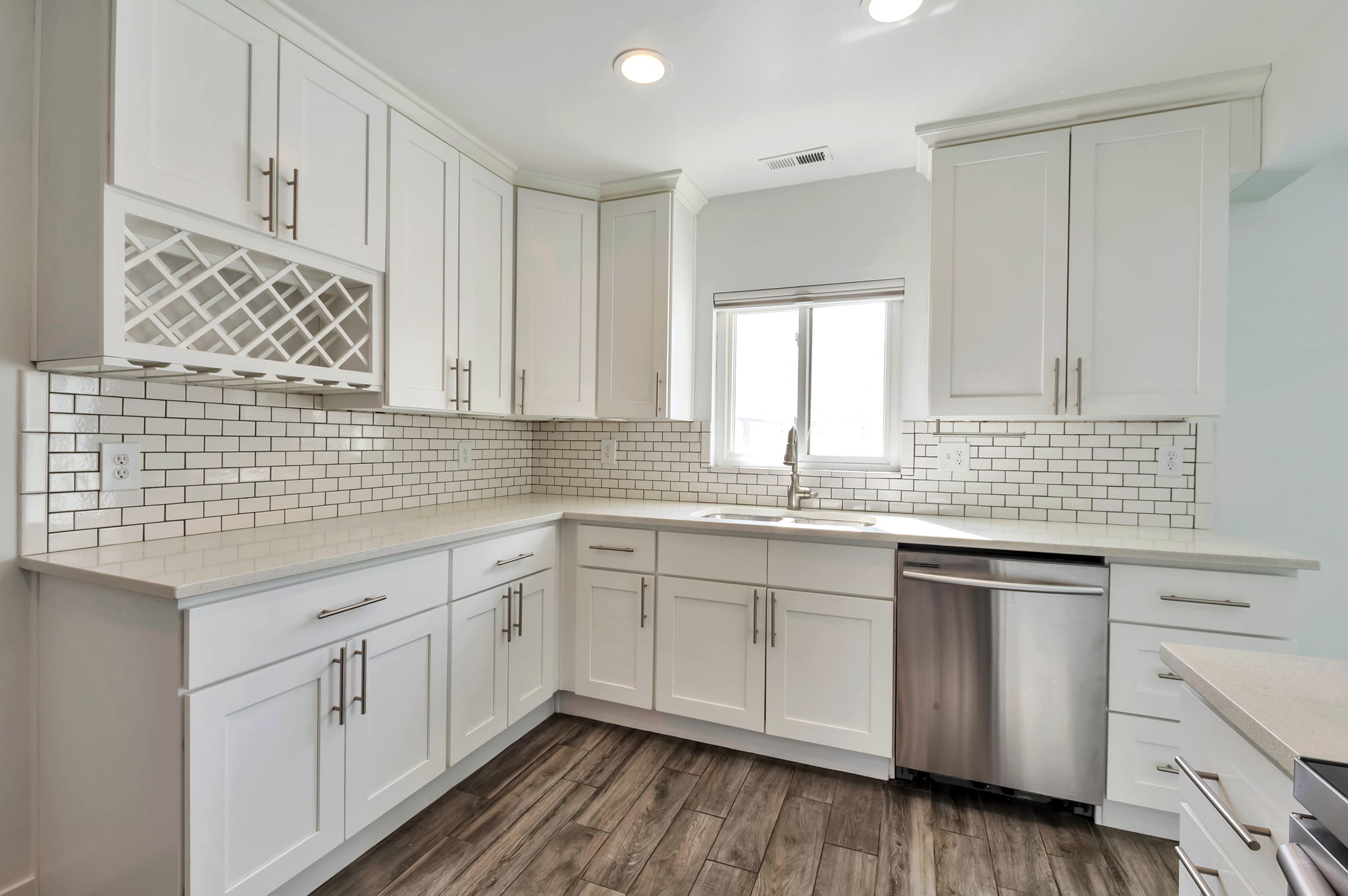 Kitchen with white cabinets, dishwasher, light stone countertops, dark wood-style flooring, and recessed lighting